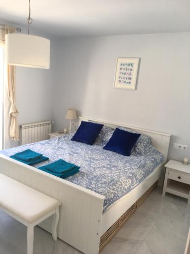 a bed with blue pillows in a white room at 2 bedroom apartment in the old town, close to the beach in L'Escala