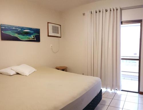 een slaapkamer met een wit bed en een raam bij Apto na quadra do mar em Meia Praia Itapema, 2 dorm, 6 pessoas in Itapema