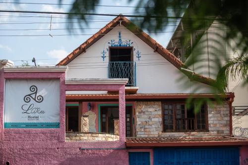 uma casa rosa e branca com um cartaz. em Hostel LARes em Brumadinho