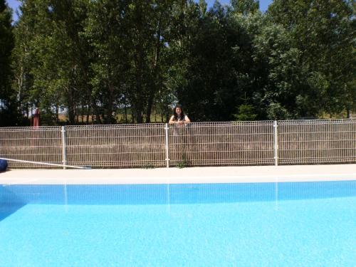 a woman standing behind a fence next to a swimming pool at Hotel Santa Coloma del Camino in Olmillos de Sasamón
