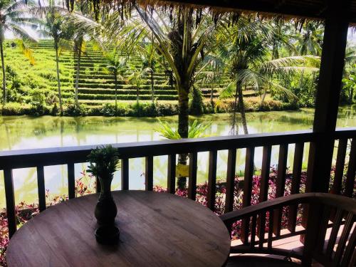 a table on a balcony with a view of the water at Alam Taman Villa in Tabanan