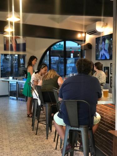 a group of people sitting at a bar in a restaurant at Hotel McCoy - Art, Coffee, Beer, Wine in Tucson