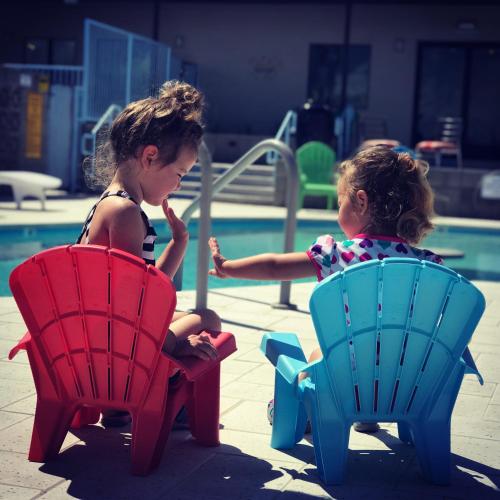 two little girls sitting in chairs by a pool at Hotel McCoy - Art, Coffee, Beer, Wine in Tucson