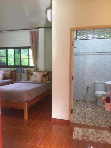 a bedroom with a bed and a bathroom with a toilet at Yayee Homestay in Sai Yok
