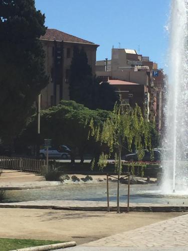 a fountain in the middle of a park with a tree at Hotel Cosmos Tarragona in Tarragona