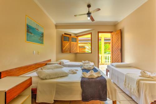 a bedroom with three beds and a ceiling fan at Pousada Raisis in Itacaré