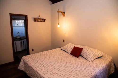 um quarto com uma cama com uma almofada vermelha em Sossego e aconchego ao lado do INHOTIM em Brumadinho