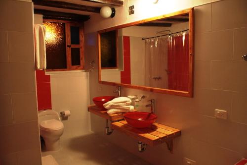 a bathroom with two red sinks and a toilet at Hotel Spa Casa de Adobe Villa de Leyva in Villa de Leyva