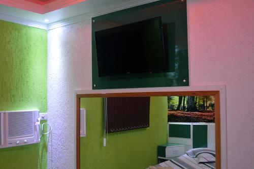 a room with a tv on the wall and a mirror at Hotel Gold in Sao Paulo