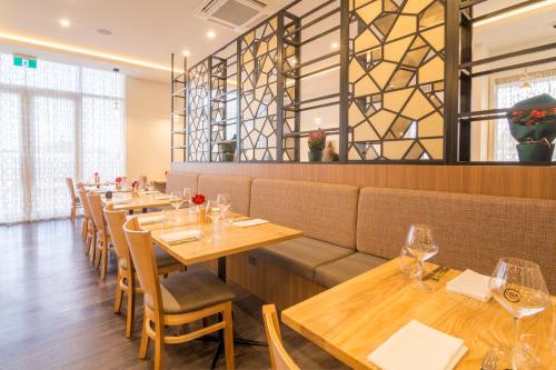 a dining room with wooden tables and chairs at The Sebel Auckland Manukau in Auckland