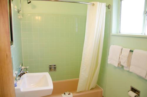 baño verde con lavabo y ducha en Budget Inn & Suites Colby, en Colby