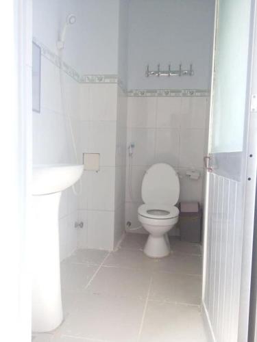 a white bathroom with a toilet and a sink at Minh Duc Guesthouse in Phan Thiet