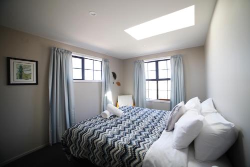 a bedroom with a bed with white pillows and windows at Pedalfish Cottages - Galaxy Views in Twizel