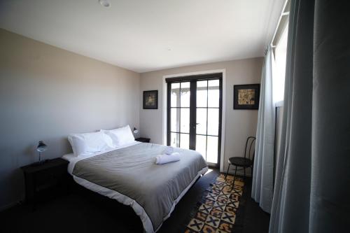 a bedroom with a bed with white sheets and a window at Pedalfish Cottages - Milky Way in Twizel