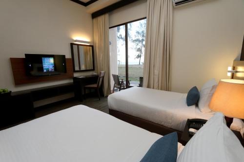 a hotel room with two beds and a tv at Villea Rompin Resort & Golf in Kuala Rompin