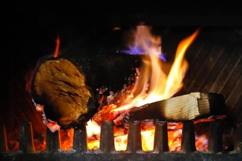 un fuego en una parrilla con carne y llamas en La CasetA, en La Pobla de Benifassà (Puebla de Benifasar)