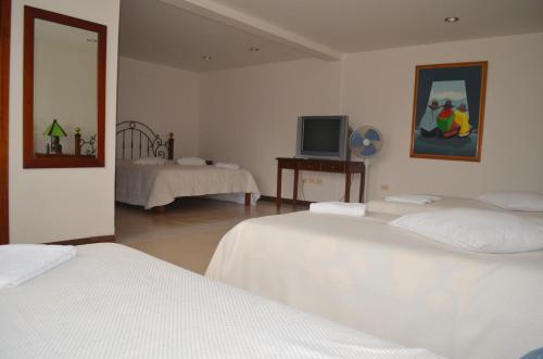 a white room with two beds and a television at Finca Hotel Valparaíso in Armenia