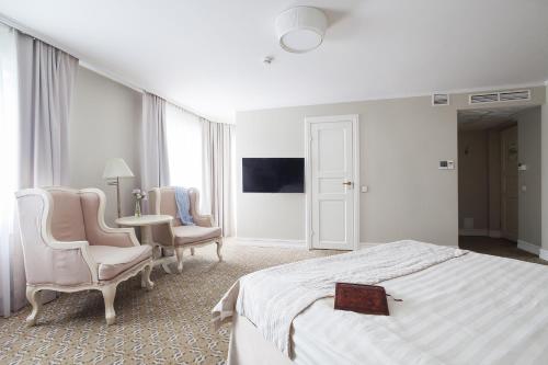 a white bedroom with a bed and two chairs at Renomme hotel by Original Hotels in Yekaterinburg