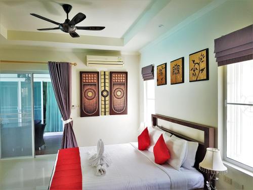 a bedroom with a bed with red pillows and a ceiling fan at Prima Villas Karon Beach by PHR in Karon Beach