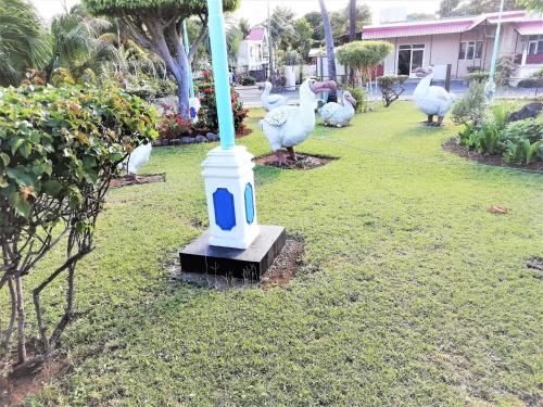 a group of birds standing around a pole in a yard at West Sand Holidays LICENSED BY THE TOURISM AUTHORITY 09926 in Flic-en-Flac
