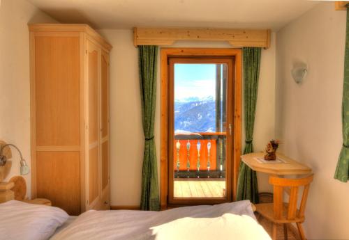 a bedroom with a bed and a door with a balcony at Panorama Restaurant Sterzingerhaus 1.930m in Vipiteno