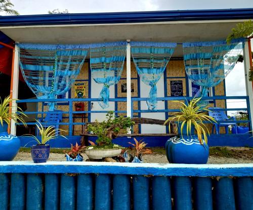 a blue building with blue curtains and potted plants at Bolo Beach Santorini nearby to Hundred Island in Alaminos