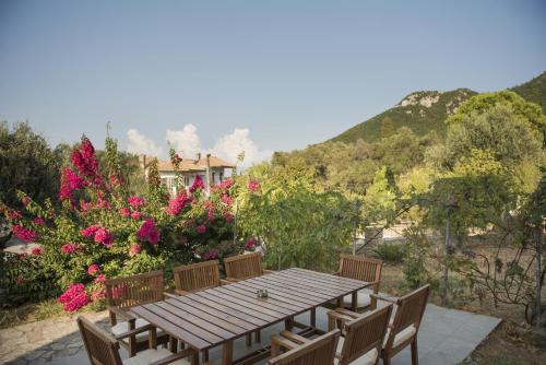 a wooden table and chairs with flowers and a house at Villa Mariza in Corfu Town