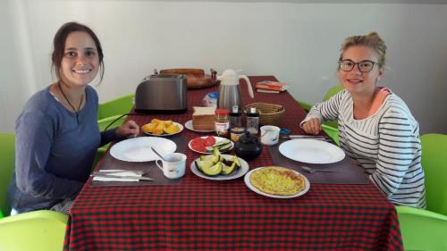 two women sitting at a table with food on it at David Crater Homestay in Lushoto