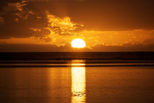 a sunset over a body of water at The Black Pearl Beachside Apartments in Rarotonga