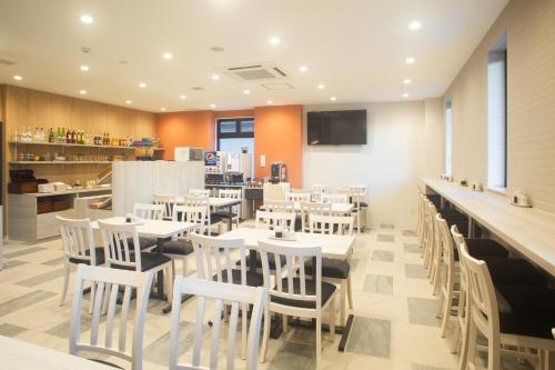 a restaurant with white tables and white chairs at Kuretake Inn Nankai Sakai-Ekimae in Sakai