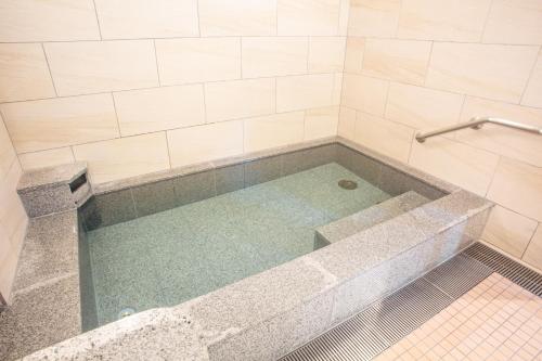 a large tub in a bathroom with a tile shower at Kuretake Inn Nankai Sakai-Ekimae in Sakai