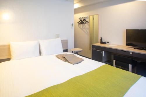 a bedroom with a bed with a desk and a television at Kuretake Inn Nankai Sakai-Ekimae in Sakai