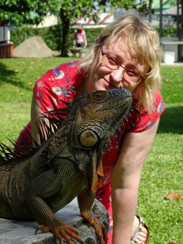 a woman is standing next to a iguana at Hotel Colores del Arenal in Fortuna