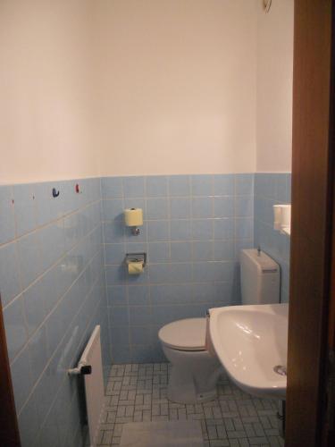a blue tiled bathroom with a toilet and a sink at Haus Hildegunde in Bad Füssing