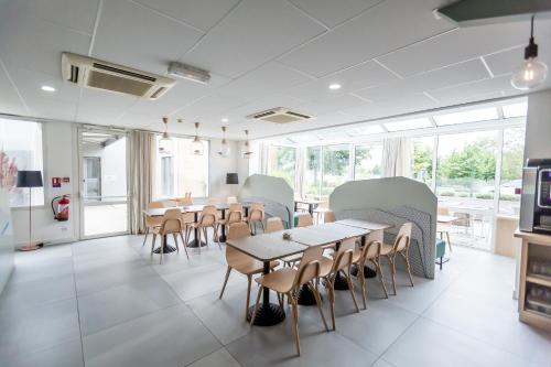 a dining room with tables and chairs and windows at Kyriad Clermont-Ferrand-Sud - La Pardieu in Clermont-Ferrand