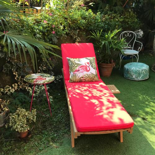 a red chair with a pillow sitting in a garden at Il Giardino Segreto Arona, Charming Apartments in Arona