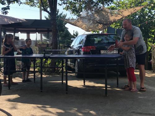 een man en een vrouw met een kind achter een tafel bij TJ Guest House in Makhinjauri