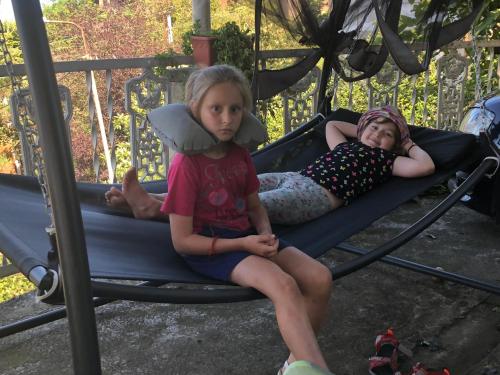 two young girls sitting on a playground swing at TJ Guest House in Makhinjauri