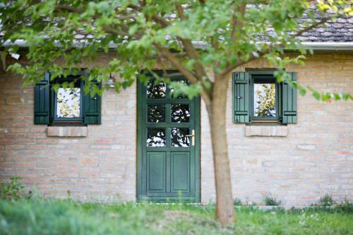a brick building with a green door and two windows at Provence Birtok in Decs