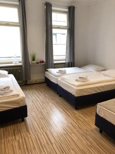 two beds in a room with two windows at Downtown City - PrivateRooms in Fürth