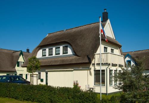 a house with a thatched roof with a car in front at Ferienhaus - Huus Holm in Breege