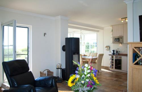 a living room with a black leather chair and a kitchen at Ferienhaus - Huus Holm in Breege