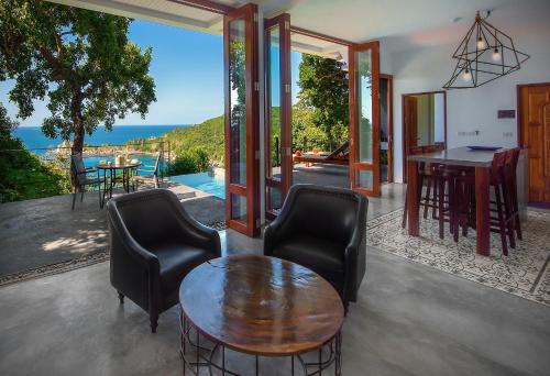 a living room with a table and chairs and a view of the ocean at Philip's Villa in Koh Tao