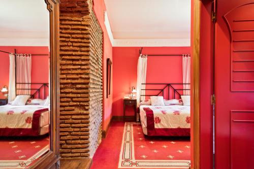 a red bedroom with two beds and a mirror at Abba Palacio de Soñanes Hotel in Villacarriedo