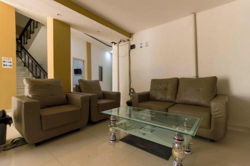 a living room with two couches and a glass table at RedDoorz at Tara Homestay Palembang in Palembang