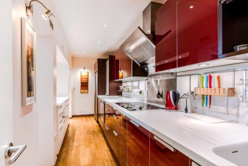 una cocina con encimeras blancas y armarios rojos en Garden Apartment in Central London, en Londres