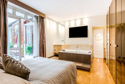 a bedroom with a bed and a tub and a television at Garden Apartment in Central London in London
