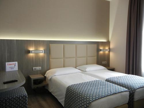 a hotel room with two beds and a desk at Delle Nazioni Milan Hotel in Milan