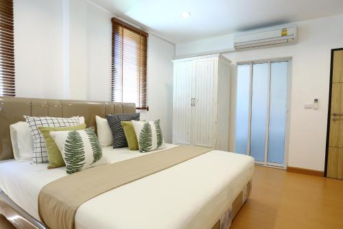 Un dormitorio con una cama grande con almohadas verdes y blancas en Thacha Pool Villa A, en Hua Hin