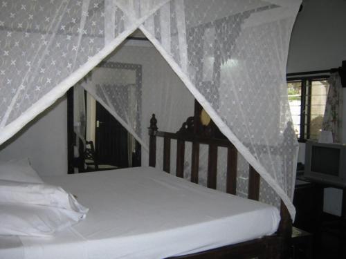 a bed with a net canopy in a bedroom at Scorpio Villas Resort in Malindi